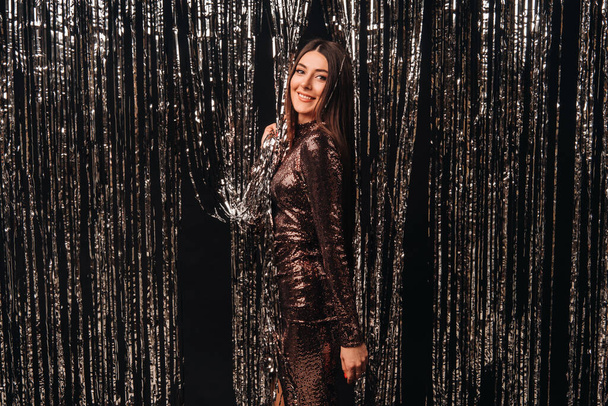 Yeni yıl yağmurunun gümüş arka planında parlak elbiseli bir kız.. - Fotoğraf, Görsel