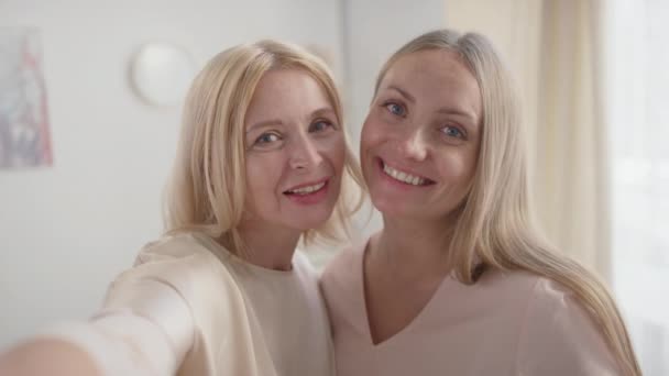 Handheld pov slowmo close-up of happy caucasian women - mother and daughter  taking selfie on smartphone smiling to camera - Materiaali, video