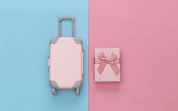 Koncepcja podróży. Mini plastikowa walizka podróżna i pudełka na różowym niebieskim tle pastelowym. Minimalny styl. Widok z góry, płaski - Zdjęcie, obraz