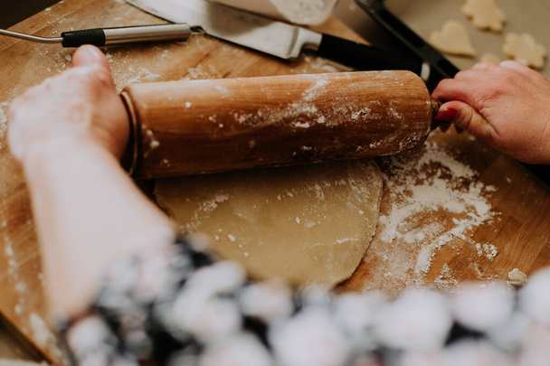 A closeup of a woman preparing the dough with a wooden rolling pin - 写真・画像