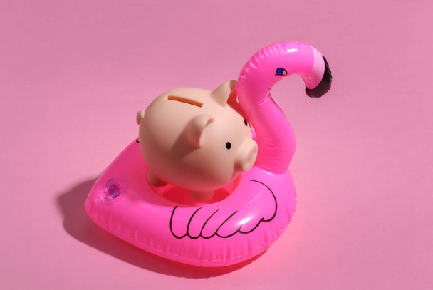 Şişirilebilir pembe flamingo ve pembe güneşli arka planda domuz kumbarası. Yaz tatili kavramı. Minimalizm - Fotoğraf, Görsel