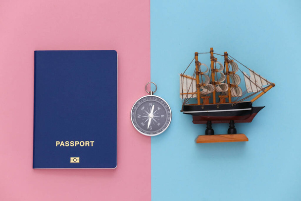 Minimalisme voyage, aventure à plat. Boussole et passeport, navire sur fond pastel bleu-rose. Vue du dessus - Photo, image