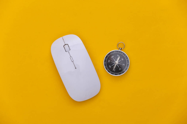 Kompass und PC-Maus auf gelbem Hintergrund. Online-Geschäft oder Reisen. Ansicht von oben - Foto, Bild