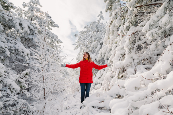 Belle femme heureuse debout parmi les arbres enneigés dans la forêt d'hiver. Femme voyageuse avec des arbres à neige - Photo, image