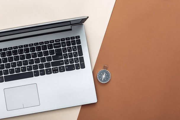 Laptop és iránytű bézs barna háttérrel. Online üzlet vagy utazás. Felülnézet - Fotó, kép