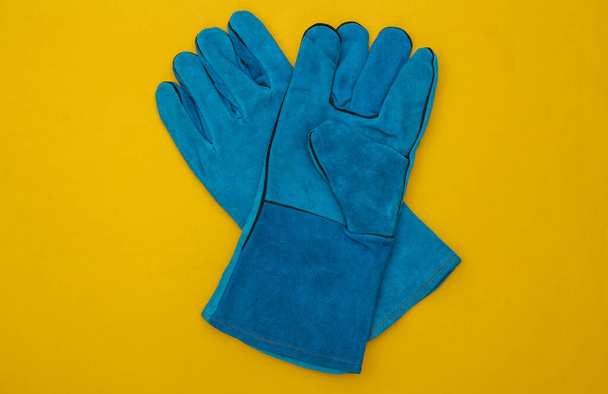 Μπλε γάντια εργασίας σε κίτρινο φόντο. Άνω όψη - Φωτογραφία, εικόνα