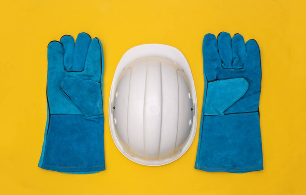 Gants de travail et casque de sécurité de construction sur fond jaune. Vue du dessus - Photo, image