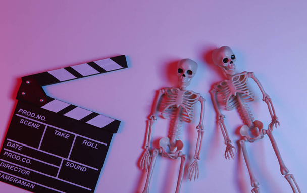 Bordo di cinepresa con scheletri in sfumatura luce rosso-blu al neon. Halloween film spaventoso - Foto, immagini