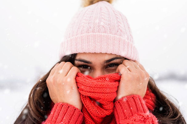 Winter season. Portrait of a beautiful smiling woman in red sweater and hat in snowy park - Fotoğraf, Görsel