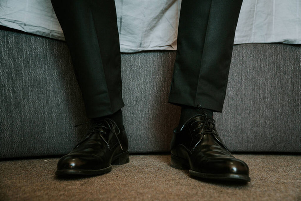 A closeup shot of the legs of a male in elegant black shiny shoes - Foto, Imagen