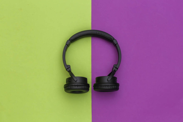 Draadloze stereo koptelefoon op groene paarse achtergrond. Bovenaanzicht - Foto, afbeelding