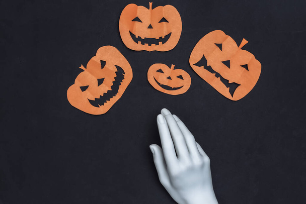 Handgemaakt papier gesneden halloween pompoen en etalagepop hand op zwarte achtergrond. Halloween thema. Bovenaanzicht - Foto, afbeelding