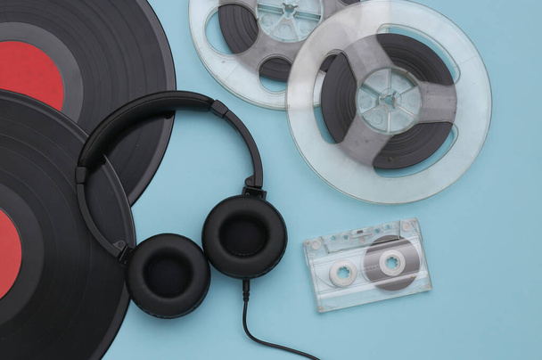 Retro-Schallplatten, Audio-Magnetspule, Audiokassette und Stereo-Kopfhörer auf blauem Hintergrund. Ansicht von oben. Flache Lage - Foto, Bild