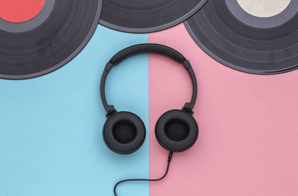 Retro-Schallplatten und Stereo-Kopfhörer auf rosa-blauem Pastellhintergrund. Ansicht von oben. Flache Lage - Foto, Bild