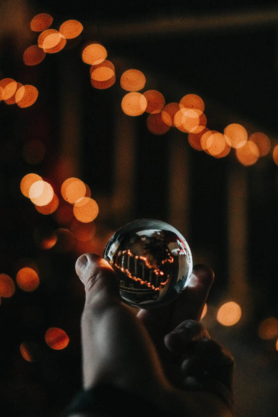 A male's hand holding a crystal ball with bokeh lights background - Photo, image