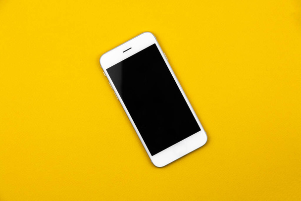 Smartphone blanco en blanco negro sobre fondo amarillo aislado, maqueta y diseño conceptual, plantilla. Foto de alta calidad - Foto, imagen