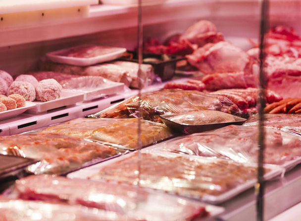 A selective focus closeup of different types of meat in plastic boxes in a shop window - Foto, afbeelding