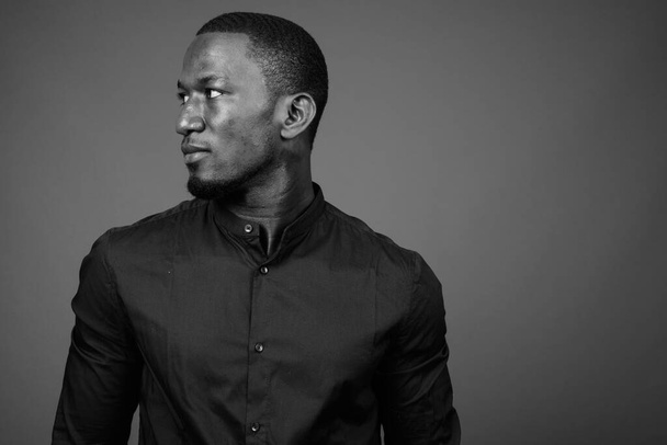 Studio záběr pohledný africký podnikatel na sobě černé tričko proti hnědému pozadí - Fotografie, Obrázek