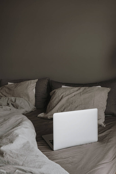 Современная концепция дизайна интерьера. Hygge style bedroom with grey washed linen bedclothes, pillows, laptop. Минималистическая скандинавская гостиная. - Фото, изображение