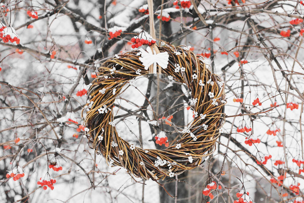 Χριστουγεννιάτικο στεφάνι στο δέντρο. Χειροποίητο στεφάνι στην πόρτα σε φόντο χειμερινών μούρων. Χειμερινή διακόσμηση. Χειμώνας Viburnum - Φωτογραφία, εικόνα