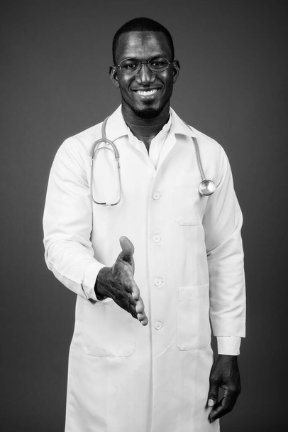Studio shot of handsome African man doctor wearing eyeglasses against brown background - Fotografie, Obrázek