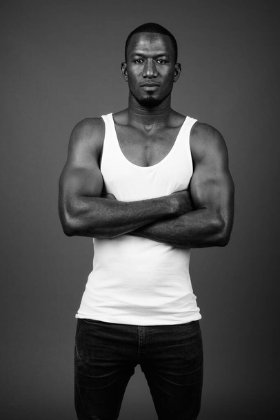 Kahverengi arka planda kolsuz bluz giyen yakışıklı Afrikalı adamın stüdyo fotoğrafı. - Fotoğraf, Görsel