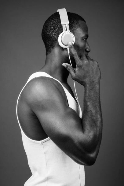 スタジオショットのハンサムな筋肉アフリカの男の音楽を聴く茶色の背景 - 写真・画像