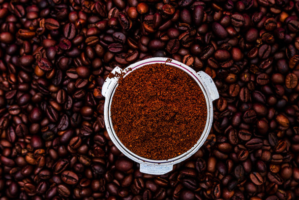 Hintergrund mit gemahlenem Kaffee im Portafilter umgeben von gerösteten Kaffeebohnen, - Foto, Bild
