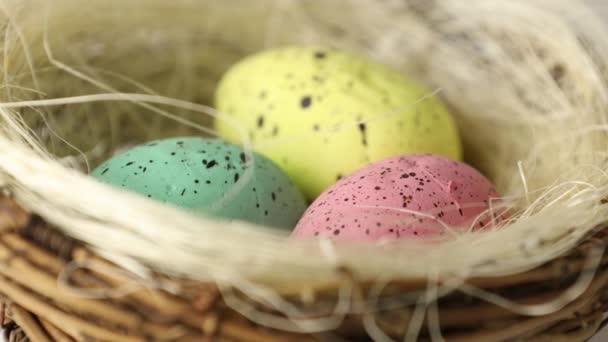 Happy Easter. Painted eggs in a basket with blooming jasmine flowers. Close up of a decorative nest with colored eggs for the Easter holiday rotating in circle. - Footage, Video