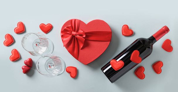 Valentijnsdag set voor feest van rode wijn en wijnglazen en hart cadeau op blauw. Zicht van bovenaf. Vlakke plaat. - Foto, afbeelding