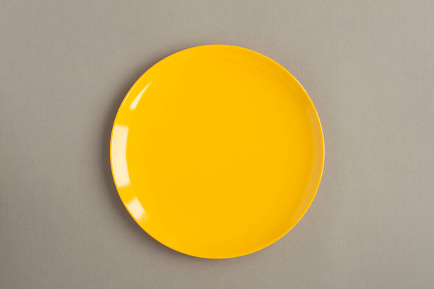 Draufsicht des leeren gelben Tellers auf dem grauen Hintergrund - Foto, Bild