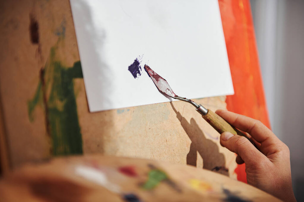 A művész nőjének keze fehér vászonra kenődik egy palettakéssel. - Fotó, kép