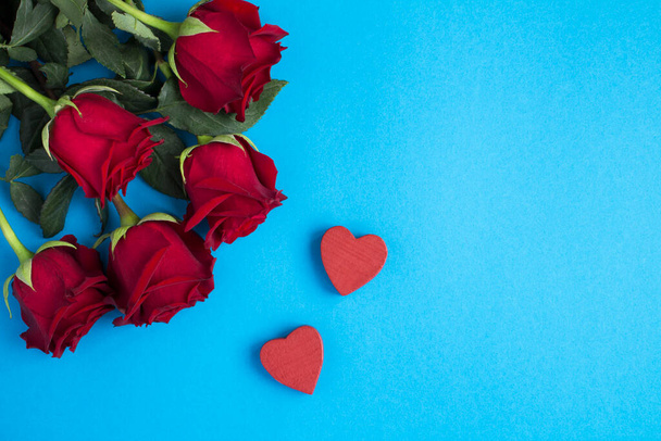 Mavi arkaplanda kırmızı güllerin ve kalplerin üst görüntüsü - Fotoğraf, Görsel