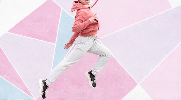 женщина прыгает перед прохладной розовой стеной - Фото, изображение