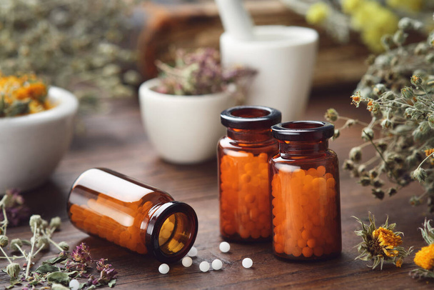 Three bottles of homeopathic globules and medicinal herbs. Homeopathy medicine concept. - Valokuva, kuva