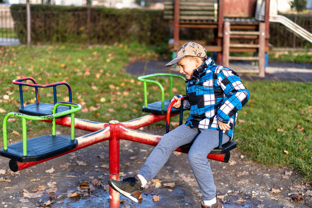 Un garçon caucasien pendant la journée froide à l'aire de jeux - Photo, image