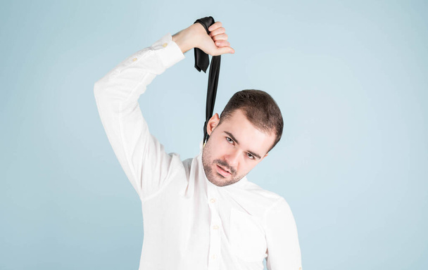 An upward-looking portrait of a bored or tired Caucasian young office manager fed up, feeling uncomfortable hanging from his tie, feigning suicide - Foto, immagini