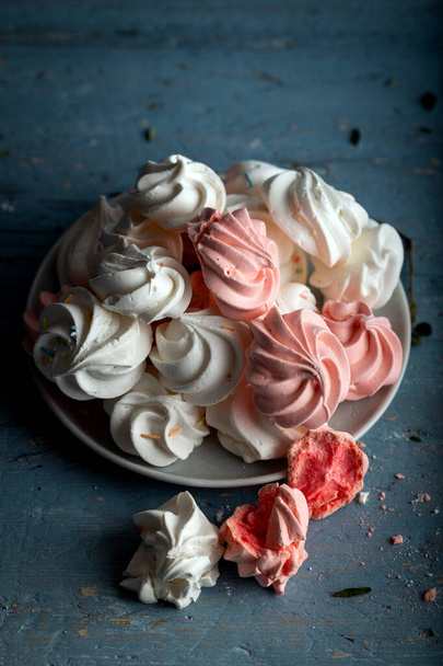 Pattern with delicate light white and pink meringue cookies on wooden background. - Photo, Image