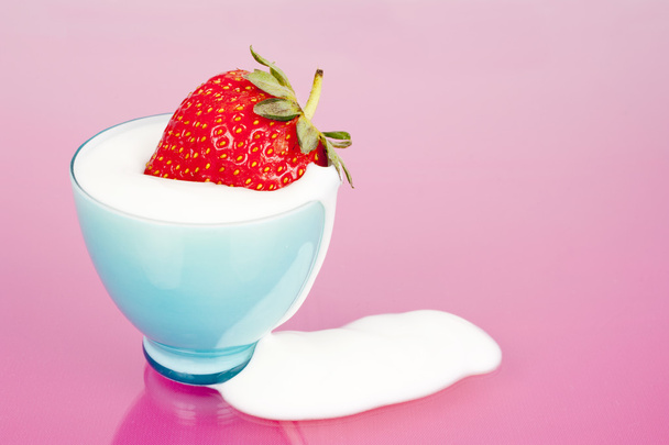 Fresa en taza azul con derrame de yogur
 - Foto, imagen