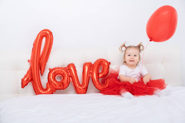 mignonne bébé fille tient l'inscription amour de ballons sur un fond blanc - Photo, image