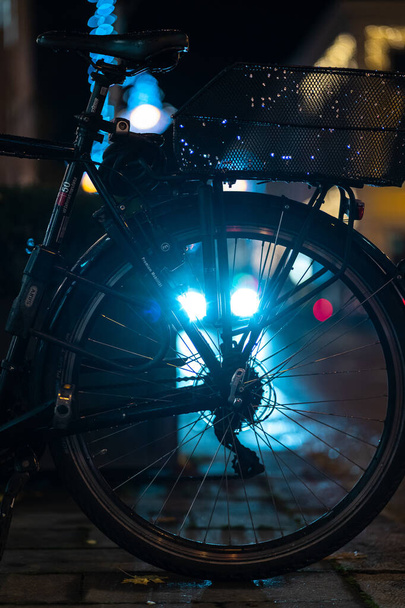 A vertical closeup of a bicycle wheel captured at night on the street - Foto, Imagen