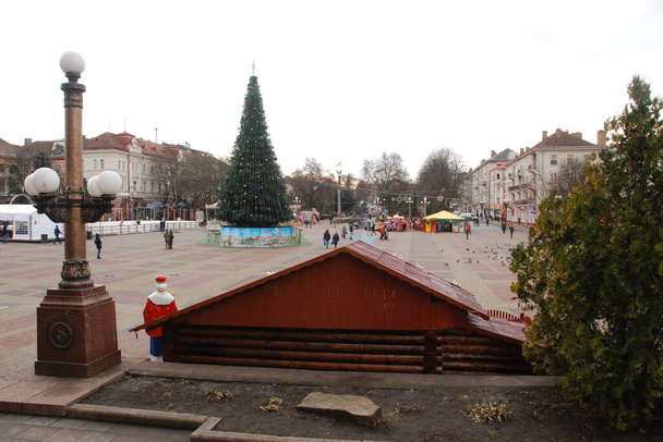 Kerstboom op het plein van de oude stad.Kerstboom, oud plein, de stad, kunstmatig, takken, bloemenslingers, algemeen uitzicht, groen, sieraden, naalden, Nieuwjaar, speelgoed, boom, stam - Foto, afbeelding