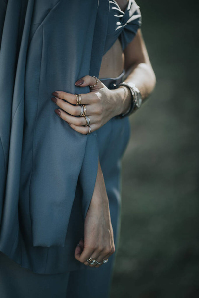 Una donna che indossa un abito elegante con le dita piene di anelli - Foto, immagini