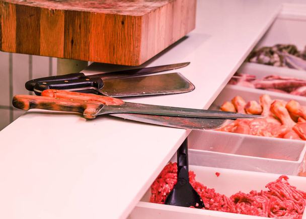 Mağazadaki çiğ etin yanında bıçakların yakın çekimi. - Fotoğraf, Görsel