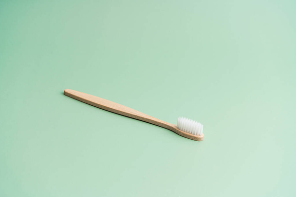 Environmentally friendly bamboo wood antibacterial toothbrush on light green background. - Valokuva, kuva