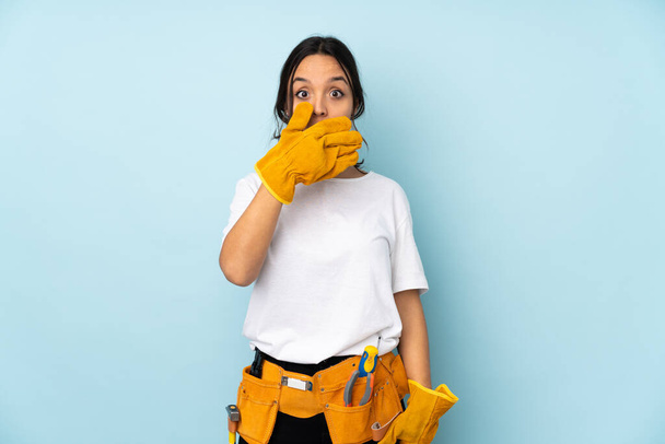 Mladý elektrikář žena izolované na modrém pozadí pokrytí úst s rukama - Fotografie, Obrázek