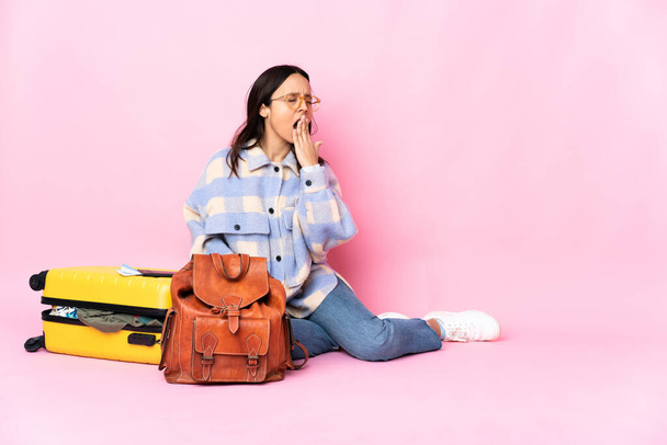 Matkustaja nainen matkalaukku istuu lattialla haukottelu ja kattaa leveä suu käsin - Valokuva, kuva