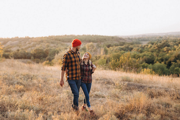 Cheerful guy and girl on a walk in bright knitted hats and plaid shirts - Photo, Image