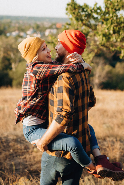 Cheerful guy and girl on a walk in bright knitted hats and plaid shirts - Фото, зображення