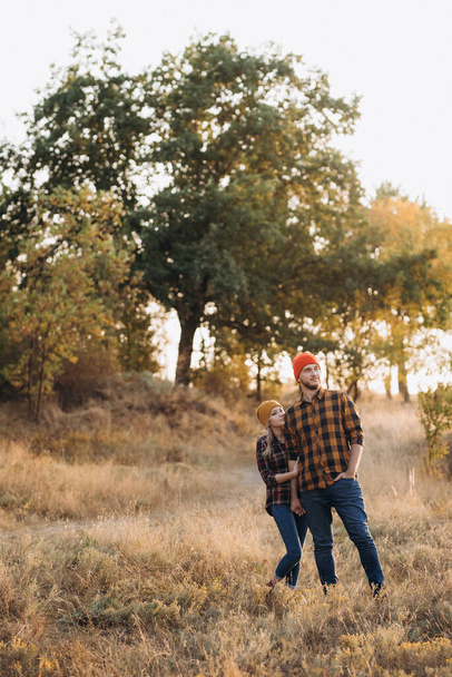 Cheerful guy and girl on a walk in bright knitted hats and plaid shirts - Fotoğraf, Görsel